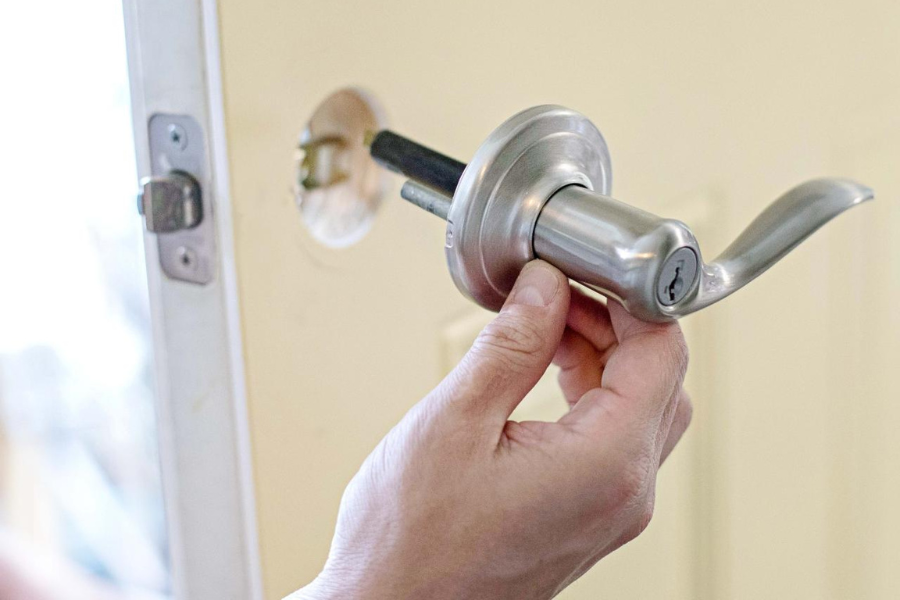 a hand placed on a door's door handle for repair